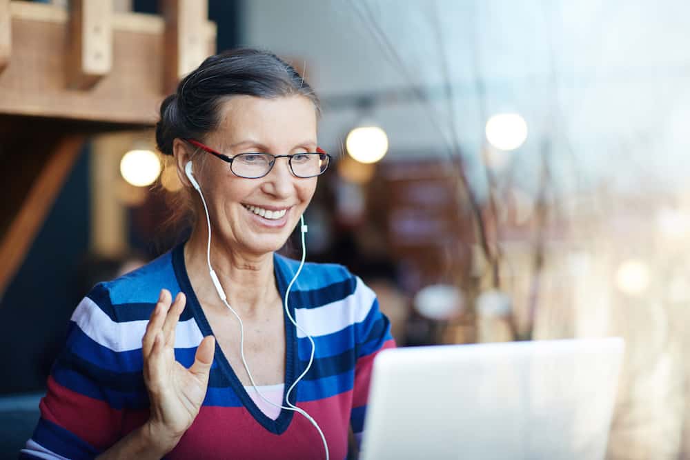 woman with headphones participating in virtual workshop on laptop