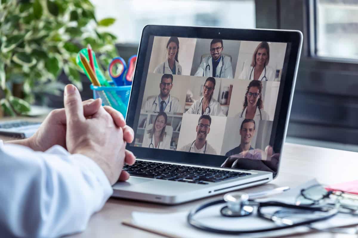 person watching video call with doctors on laptop